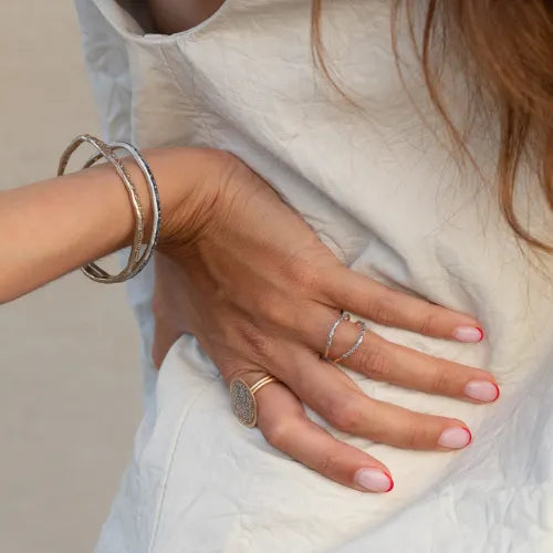 femme portant plusieurs bagues et bracelets argentés
