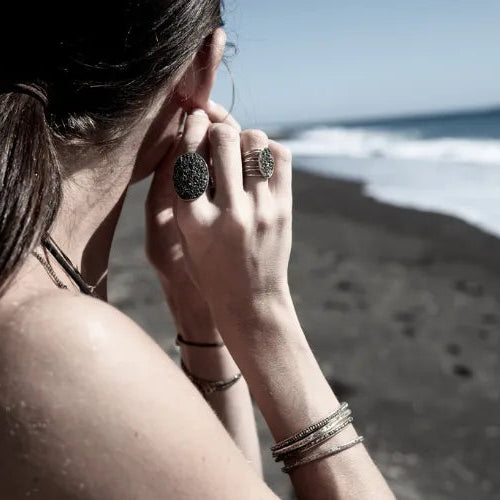 femme sur la plage portant un ensemble de bracelets et bagues foncés