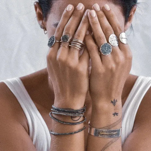 femme au visage caché portant des bijoux noirs et argentés