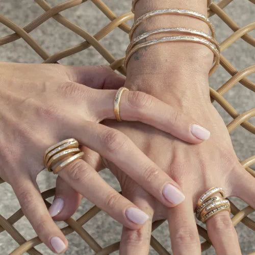 main féminine ornée de bagues dorées et bracelets design