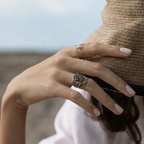 Bague Spirale Minéral LSonge vue en extérieur – main avec chapeau et bague pierre dorée