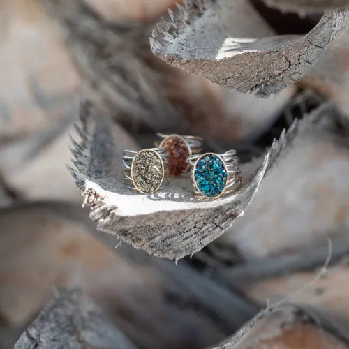 Trois bagues Spirale Minéral LSonge posées sur une écorce – pierres naturelles bleu, or, cuivré